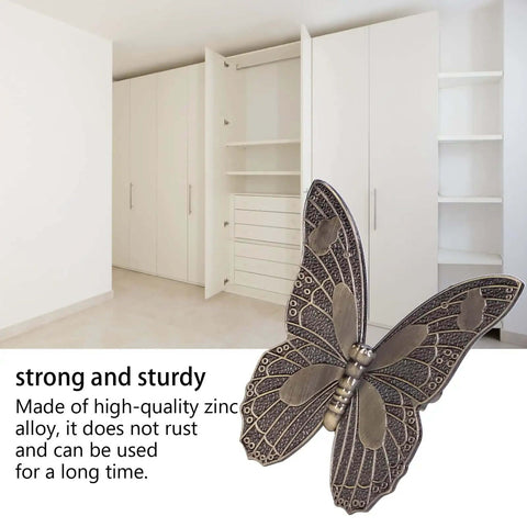Decorative butterfly-shaped zinc alloy hardware in front of open white cabinet doors, emphasizing durability and style.