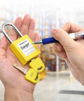 Person holding yellow padlock from 10 Pack Lockout Tagout Locks With Unique Keys Per Lock Yellow Padlocks For Lockout Tagout Stations And Devices Durable Industrial Grade OSHA Compliant Keyed Different 2 Keys Per Lock with attached keys.