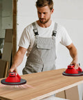 Man using Cordless Vacuum Lifter For Glass And Tile with 21 Cm NBR Base on wooden surface