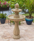 Stone garden fountain with two-tier design on patio near plants and pond