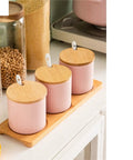 Top Shelf Ceramic Coffee Storage Jar With Secure Wooden Lid And Airtight Design Keeps Daily Grind Sugar Salt Tea Fresh As Ever While Looking Slick On Any Modern Counter Space. Pink jars with wooden lids on bamboo tray.