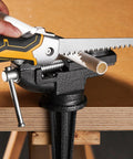 Front view of folding drywall jab saw with yellow/black soft-grip handle and serrated blade, cutting PVC pipe in a vise.