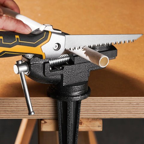 Front view of folding drywall jab saw with yellow/black soft-grip handle and serrated blade, cutting PVC pipe in a vise.