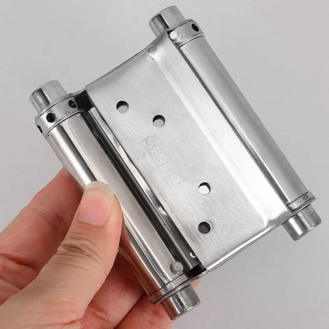 Hand holding Stainless Steel Beefy Double Spring Self Closing Door Hinges 2 Pack With Automatic Closing Versatile Exterior Door And Fence Hardware Heavy Duty Weatherproof Silver Finish.