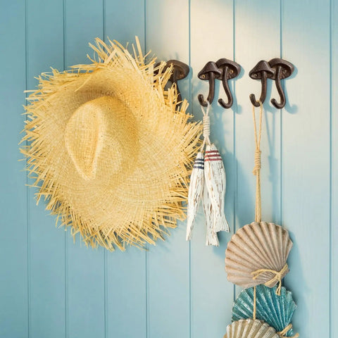Straight Up Legit Mushroom Wall Hooks Set Of Two Heavy Duty Cast Iron Coat Hangers With Antique Black Finish holding a straw hat and decor.