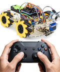 Remote-controlled robot car with visible electronics and four yellow 60mm Mecanum wheels, controlled by a pair of hands holding a controller.