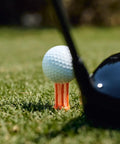 Golf ball on unbreakable premium plastic golf tee for straighter drives; consistent height, 2 in size; driver club head visible