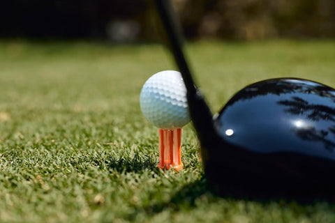 Golf ball on unbreakable premium plastic golf tee for straighter drives; consistent height, 2 in size; driver club head visible