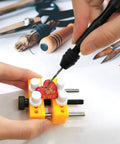 Person using Pin Vise Hand Drill Set With Bench Vise 0.5 To 3mm PCB Mini Twist Drill Bits on a small red object in a yellow vise