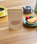 Kraft Paper Stand Up Pouches With Clear Window Pack Of 50 Reusable Sealable Bags on table with tea and fruit