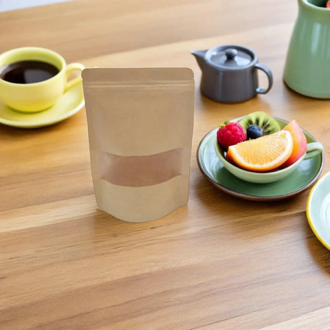 Kraft Paper Stand Up Pouches With Clear Window Pack Of 50 Reusable Sealable Bags on table with tea and fruit