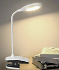 Clip On LED Desk Lamp With Battery Power Cordless Bedside Light on desk with books, flexible arm showing illuminated lamp.
