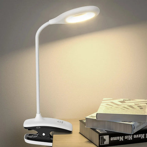 Clip On LED Desk Lamp With Battery Power Cordless Bedside Light on desk with books, flexible arm showing illuminated lamp.