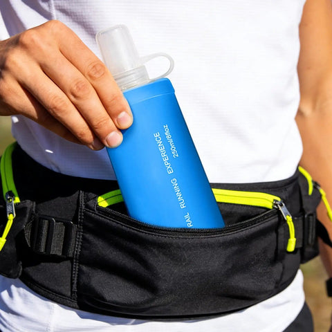 Person placing blue Foldable Soft Water Bottle That Is Leakproof And Packable For Travel Hikes And Camping into black waist bag