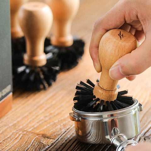 Hand using 58mm Portafilter Cleaning Brush for Espresso Machines Pro Barista Tool with arc bristle design on portafilter.