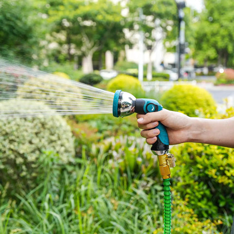High Pressure Metal Garden Hose Nozzle With 10 Spray Patterns And Thumb Control On Off Valve For Car Wash Plants Pets And Outdoor Cleaning Built For Home Use And Heavy Duty Tasks Blue being held and used to spray water on garden plants.