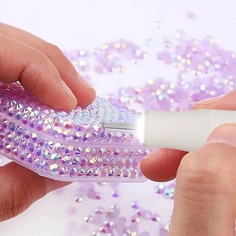 Person using Badass Cordless Electric Pickup Pen With Reliable Vacuum Grip To Snag Loose Bits on a sparkly purple surface.