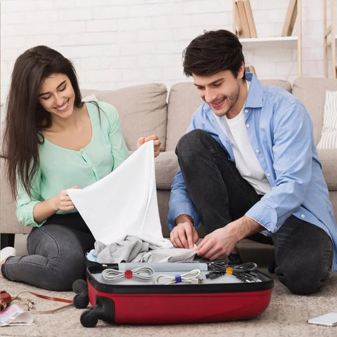 Couple using 102 Piece Reusable Hook And Loop Cable Ties Set to organize cables in a suitcase for travel.