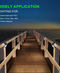 Solar Fence Lights 12 Pack Outdoor Waterproof Deck Lights installed along a wooden pathway railing at sunset.
