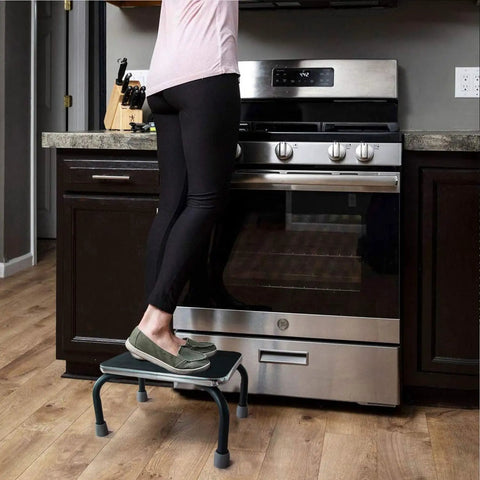 Woman using Heavy Duty Metal Step Stool For Adults And Seniors Portable Non Slip Foot Stool With 250 Lb Capacity Pre Assembled For High Beds Cars And Cabinets Safe Stable Support in kitchen