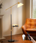 Modern standing lamp with beige shade, black and gold finish, remote control, next to brown leather chair in living room