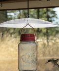 Weatherproof Outdoor Bird Feeder Cover Dome That Hangs As A Protection Shield over glass jar feeder in natural setting
