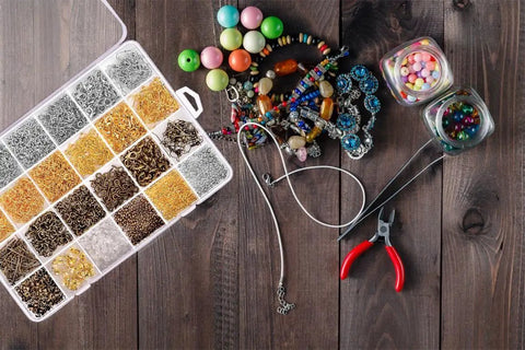 Jewelry Findings Kit With 2880 Pieces Including Open Jump Rings, Lobster Clasps, Crimp Beads, Screw Eye Pins, Head Pins, Earring Hooks And Earring Backs For DIY Jewelry Making in organized case on wooden table with beading tools and beads