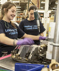 Two workers assembling washing machine valves in a factory setting.