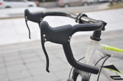Close-up of ergonomic forged aluminum drop handlebar brake levers set for road and fixie bikes with quick release on a bike.
