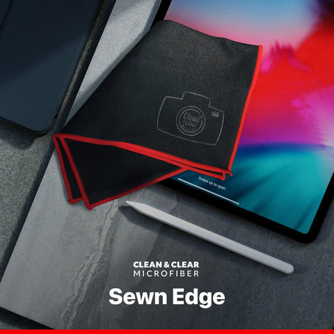 Camera lens microfiber cleaning cloth, sewn edge, black with red border, beside tablet and stylus.