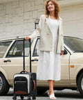 Woman standing with Underseat Carry On Luggage With Wheels 16 Inch Softside Spinner 18 By 14 By 8 Inches Travel Bag With TSA Lock.
