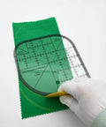 Hand using Clear Acrylic Quilting Ruler With Templates And Curved Corner Cutter For Precise Fabric Cutting on green fabric