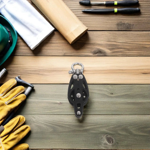 Rugged Nylon Pulley Block With Bearing For Boats And Kayaks on wooden background, surrounded by tools and safety gear.