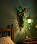 Fairy Lamp Vintage Wall Sconce, Hand-Painted Wing Design Dimmable, green illuminating a bedroom with frosted globe and leaves.