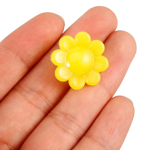Hand holding a yellow flower-shaped luminous plastic clip, Colorful Flower Bike Spoke Beads Clip On Neon Glow In The Dark Decorations.