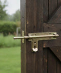 Badass Heavy Duty Slide Bolt Latch For Secure Garden Gates Barn Doors And Tight Garage Closures Featuring Smooth Manual Operation And Rust Proof Weathered Coating, installed on a wooden door.