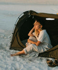 Woman sitting by tent at beach with Portable Round Camping Lantern With LED Lights For Outdoor Use Waterproof Tent Light
