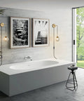 Plug In Wall Sconce Set Of 2 Modern Glass Globe Lights With Brushed Brass Finish in a bathroom setting with bathtub and art