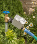 Smart Hose Watering Timer with auto scheduling attached to garden hose for precise timed watering amidst plants and flowers