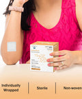 Box of 50 Bordered 2x2 Sterile Adhesive Gauze Pads for Wound Protection with one pad applied to woman's arm
