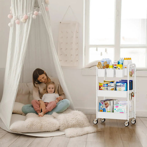 White metal 3 tier rolling cart with lockable wheels holding various items, next to a seated woman and child in a cozy room.