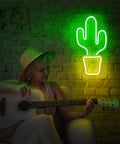 Green cactus-shaped neon light wall decor next to person playing guitar, similar style to Neon Bar Sign Premium Acrylic Cocktail Glass Light for Home Bar Pub Party Wall Decor 16.5 x 8.7 Inch Neon Lights for Business to Make Your Spot Pop and Attract More Customers