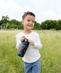Keep Things Chill In Backpacks With This Kid Approved Confetti Insulated Water Bottle Packed With A Leak Proof Straw Lid And Double Wall Stainless Steel Build For Little Ones 14 Oz. held by smiling child outdoors.