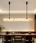 Artpad 47.24-Inch Modern Long Marble Dining Pendant Light, Suspension Lamp above a dining table with a black kettle.