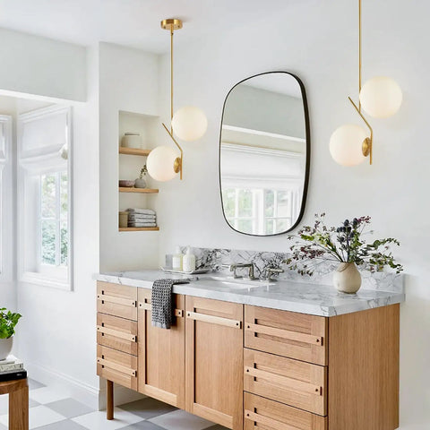 Two Light Glass Globe Pendant Light In Brushed Brass Gold Finish Modern Mid Century Style For Kitchen Island Large White Glass Globes Round Hanging Ceiling Light Sleek Contemporary Fixture over a kitchen countertop.
