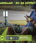 Beefy Portable Camping Light With 14000mAh Battery on table, charging phone at campsite, highlighting SOS mode.