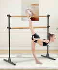 Child using 4 Foot Height Adjustable Freestanding Wooden Ballet Barre With Double Bar Heavy Duty For Your Home Gym Dance Barre Portable 350 Lb Capacity For Stretching Practice And Everyday Fitness in home studio.