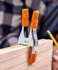 Close-up of 2 Inch Spring Clamp With Handle One Handed Clamping Tool Silver Orange Finish Quick Release Paddle Action gripping wood.