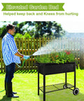 Man watering Raised Garden Bed On Legs With Wheels For Outdoor Plants An Elevated Planter Box Cart With Durable Powder Coated Metal Frame