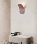 Modern Led Wall Sconce Featuring Smooth Iron Body And Soft Acrylic Diffuser, positioned above a gray upholstered bench.